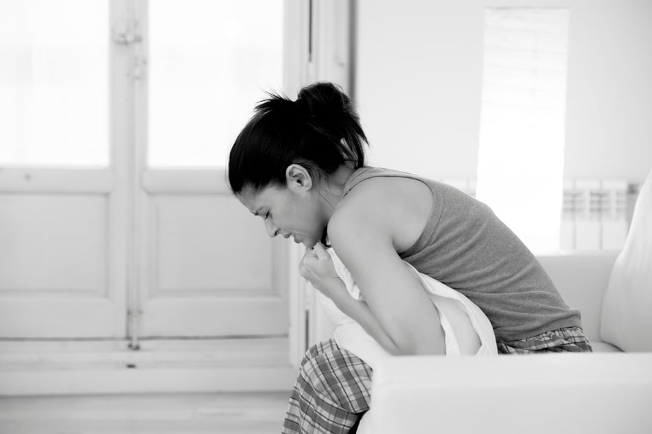 beautiful hispanic woman suffering menstrual period pain at home couch